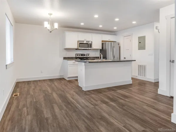 a kitchen with stainless steel appliances granite countertop a stove top oven a sink dishwasher and a refrigerator with wooden floor