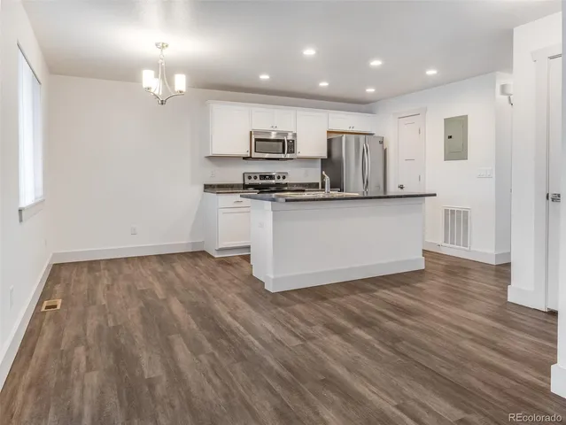 a kitchen with stainless steel appliances granite countertop a stove top oven a sink dishwasher and a refrigerator with wooden floor