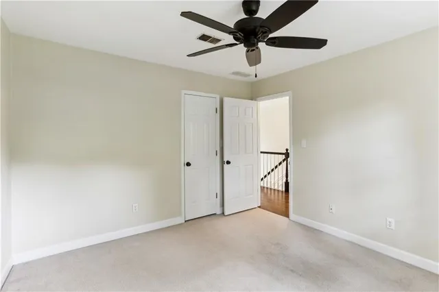 an empty room with a ceiling fan and carpet