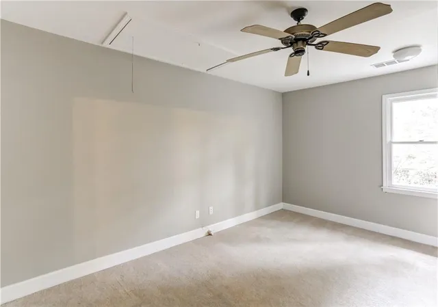 an empty room with a window and a fan