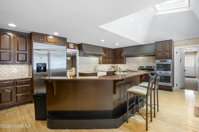 a kitchen with stainless steel appliances granite countertop a sink a stove a refrigerator cabinets and chairs