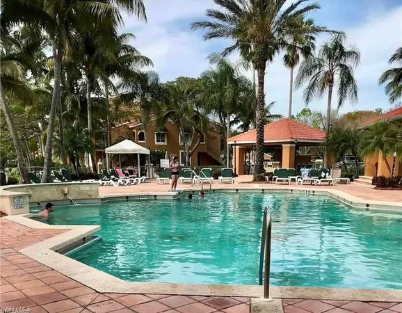 a view of a swimming pool with a table and chairs under palm trees