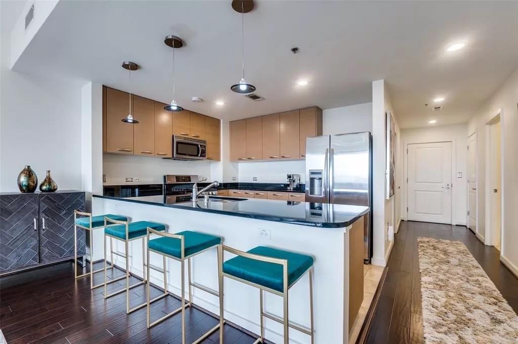 1200 Main Street, Unit 1404 Dallas, TX 75202 - Photo 11 of 27 a large kitchen with kitchen island a large counter top stainless steel appliances and cabinets