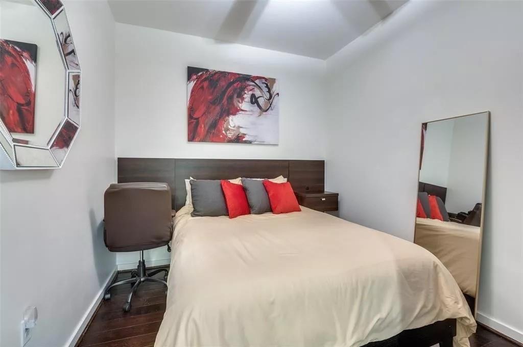 1200 Main Street, Unit 1404 Dallas, TX 75202 - Photo 17 of 27 a bedroom with a bed and a chair with the wooden floor