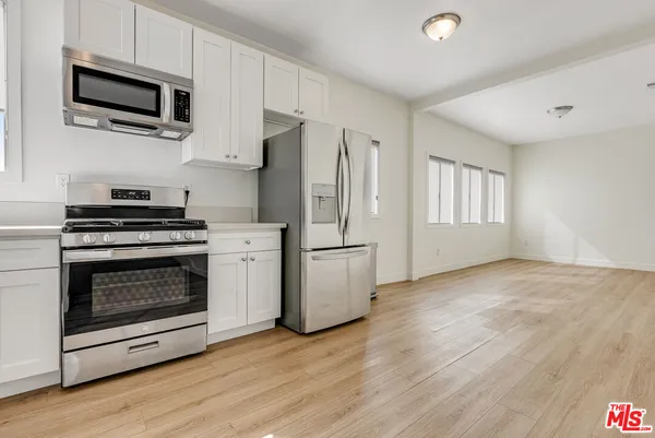 a kitchen with stainless steel appliances white cabinets a stove top oven