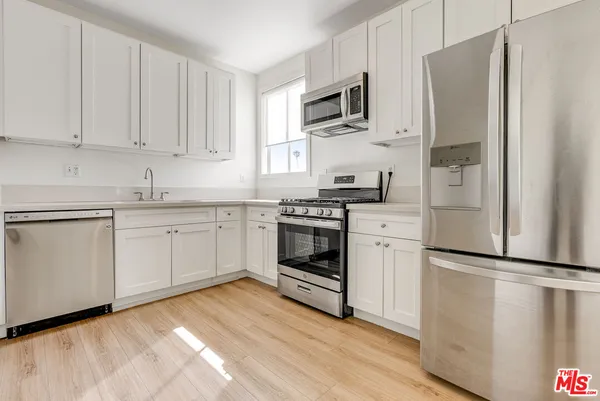 a kitchen with white cabinets stainless steel appliances and a refrigerator