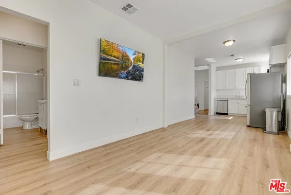 a view of empty room with wooden floor and a bathroom