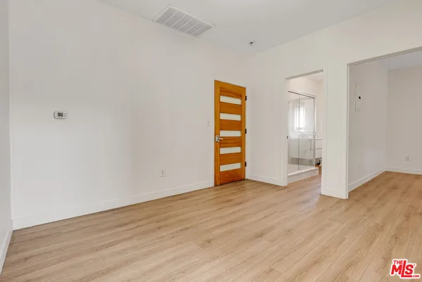 a view of an empty room with wooden floor and closet