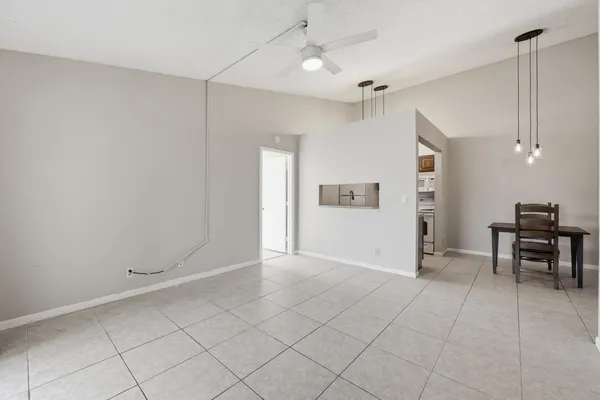 a view of an empty room with window and chandelier fan