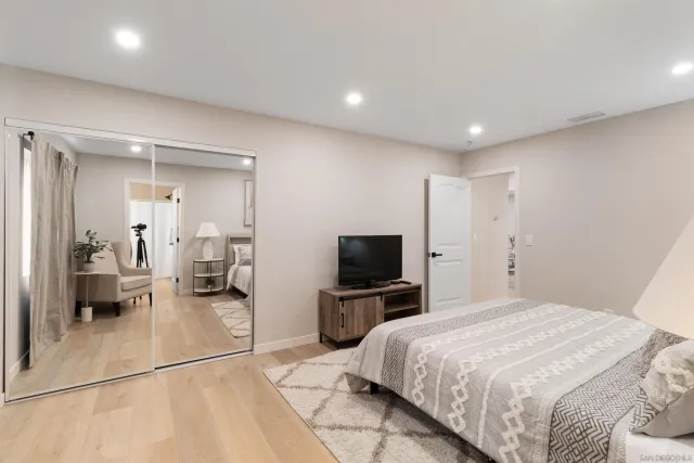 a spacious bedroom with a bed a mirror and a television on desk