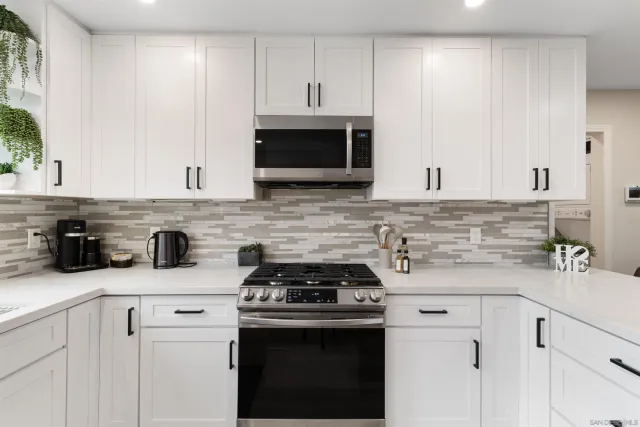 a kitchen with granite countertop a stove a sink and a microwave