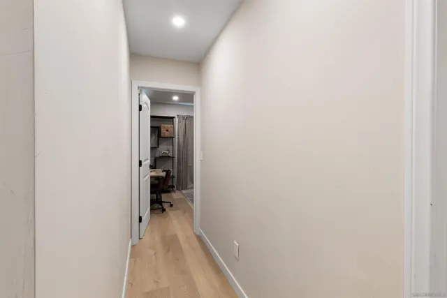 a view of a hallway with wooden floor and a bathroom
