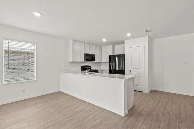 a view of kitchen with microwave a refrigerator and a stove top oven