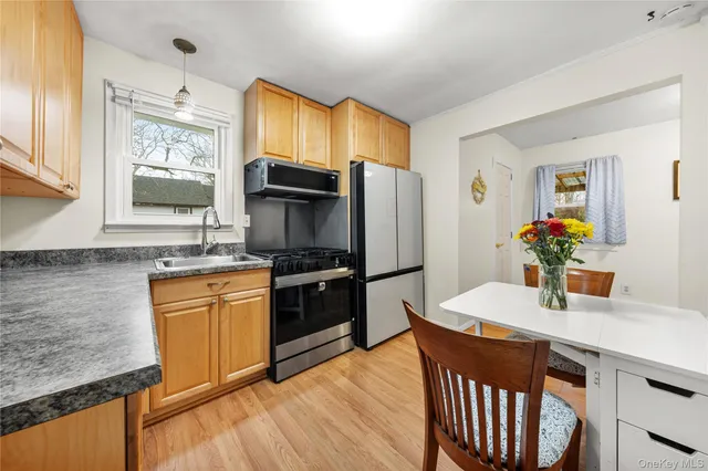 a kitchen with stainless steel appliances granite countertop a sink dishwasher a stove and a refrigerator with wooden floor