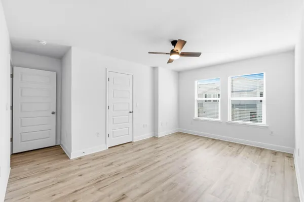 a view of an empty room with a window and wooden floor
