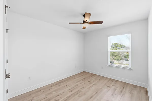 an empty room with a window and ceiling fan