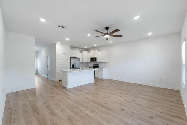 a view of kitchen with kitchen island stainless steel appliances refrigerator sink and cabinets