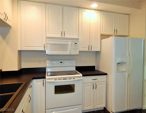 a kitchen with granite countertop white cabinets and white appliances