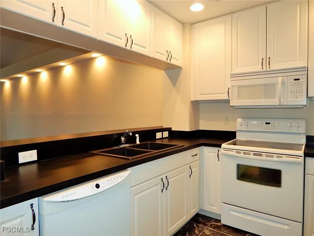 a kitchen with granite countertop cabinets and white appliances