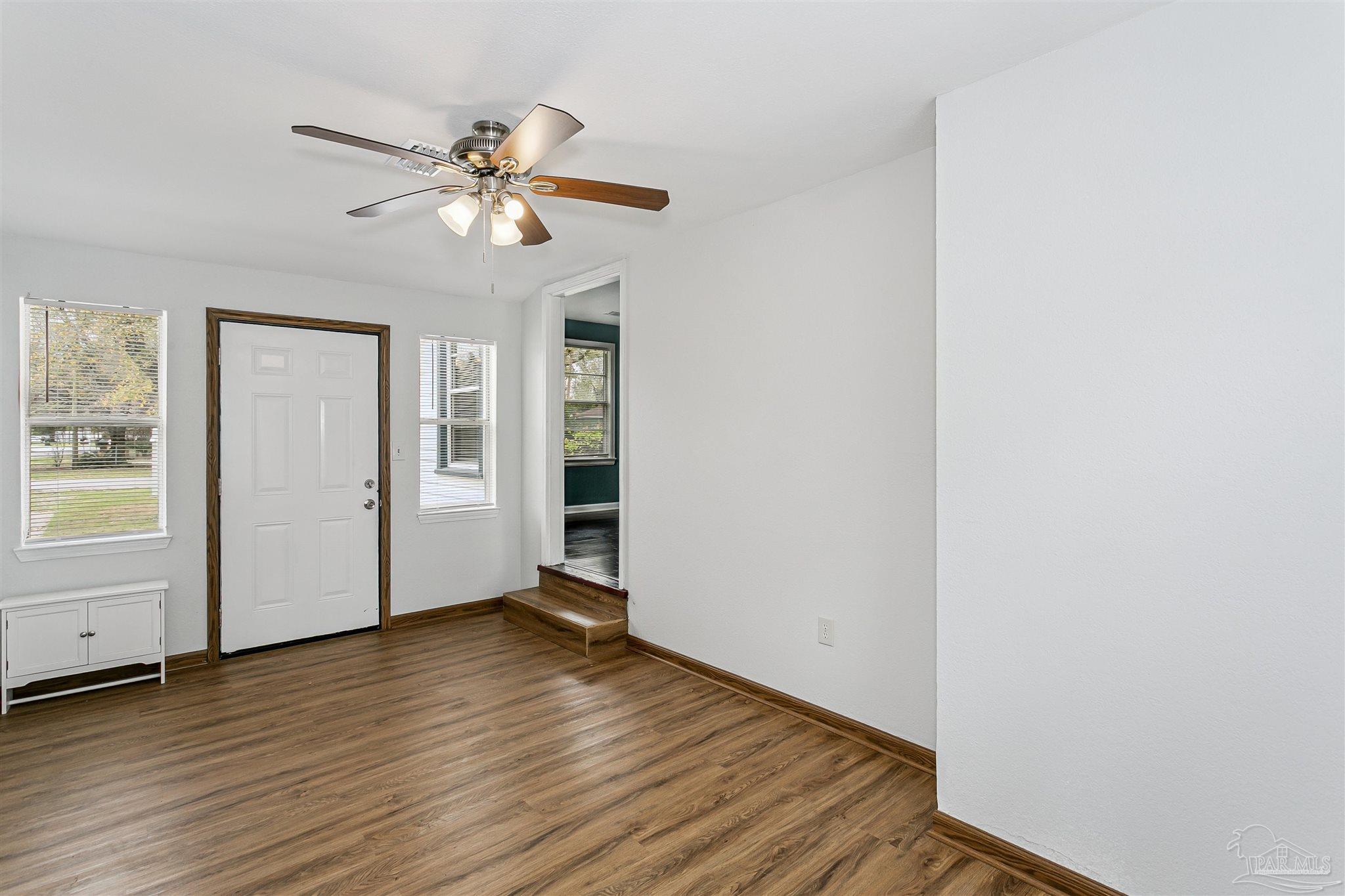 100 Milton Road Pensacola, FL 32507 - Photo 25 of 28 an empty room with wooden floor chandelier fan and windows