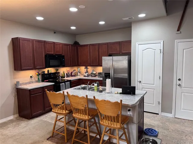 a kitchen with granite countertop a refrigerator a stove a sink a dining table and chairs