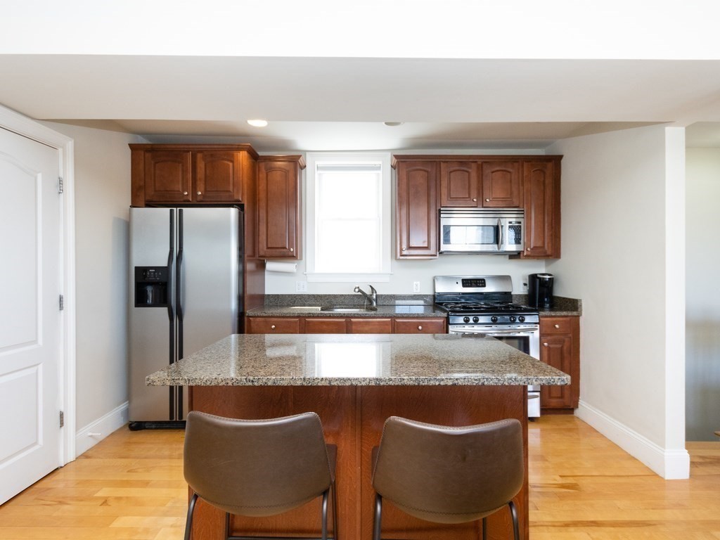 a kitchen with stainless steel appliances granite countertop a stove a refrigerator a sink a dining table and chairs