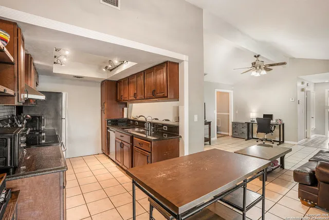 a open kitchen with stainless steel appliances granite countertop a stove top oven a sink a dining table and chairs