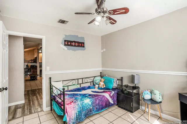 a bedroom with furniture and a chandelier fan