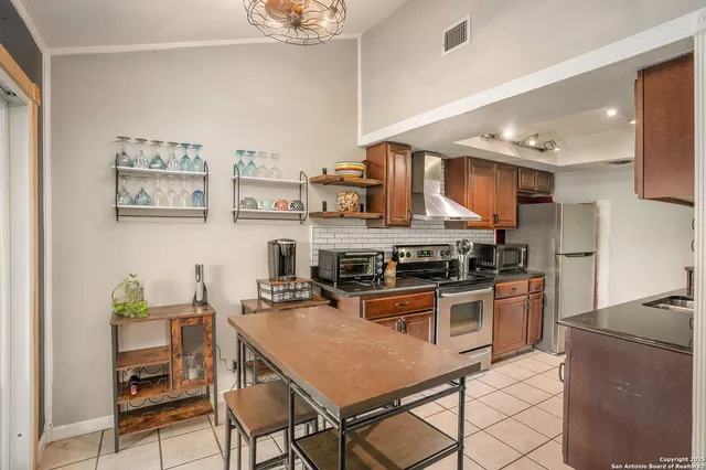 a kitchen with stainless steel appliances granite countertop a stove top oven a sink a dining table and chairs with wooden floor