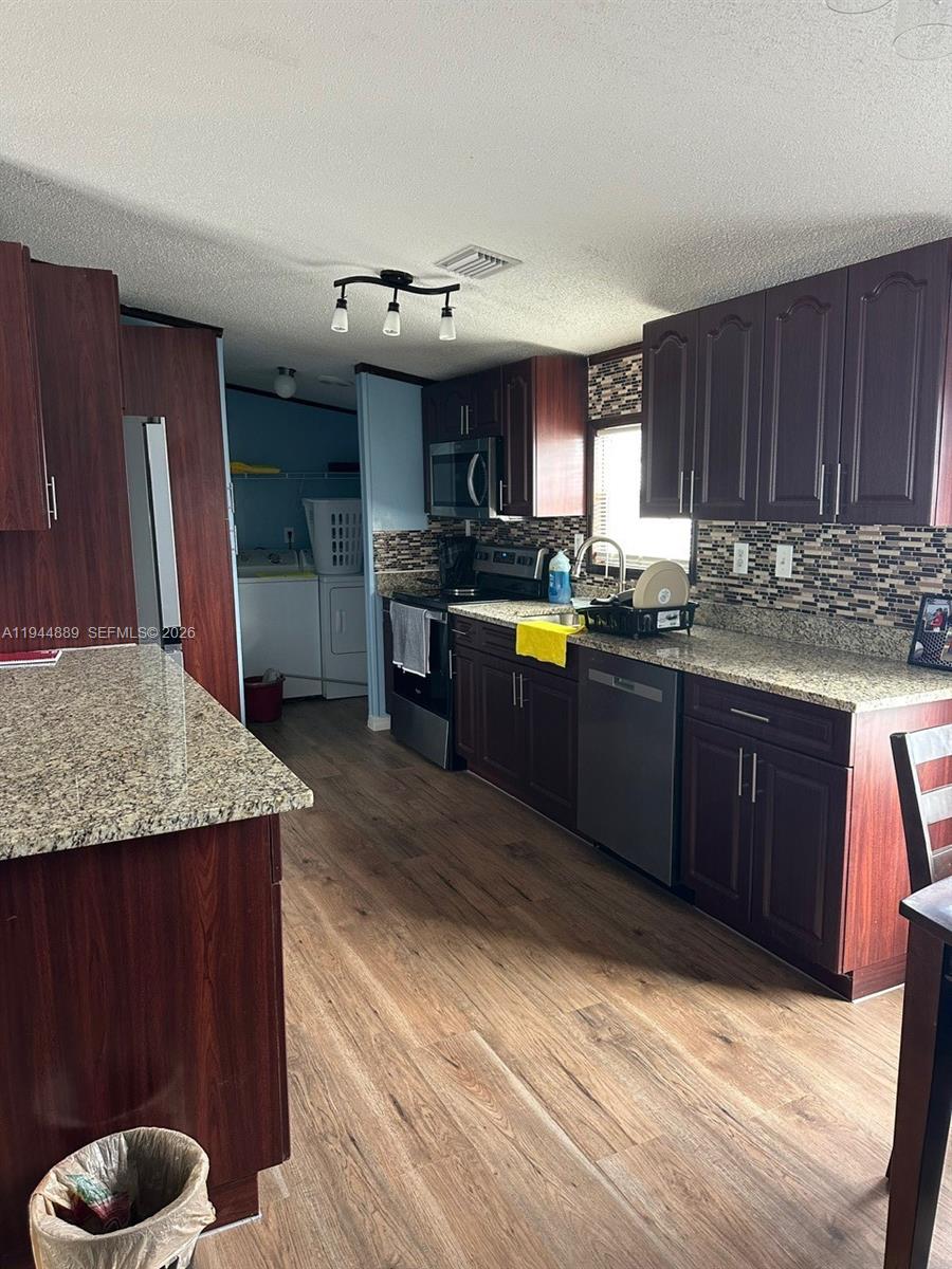 1122 Johnson Road Clewiston, FL 33440 - Photo 5 of 26 a kitchen with stainless steel appliances granite countertop a sink dishwasher stove and refrigerator with wooden floor