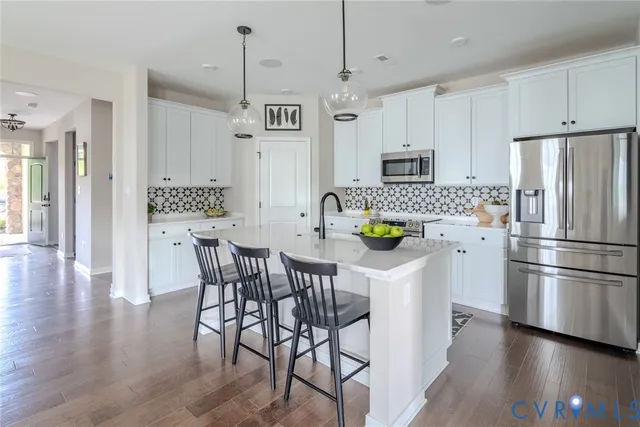 a kitchen with stainless steel appliances a dining table chairs refrigerator and sink