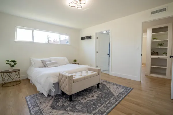 a spacious bedroom with a bed and wooden floor