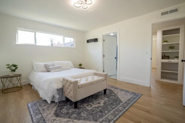 a spacious bedroom with a bed and wooden floor