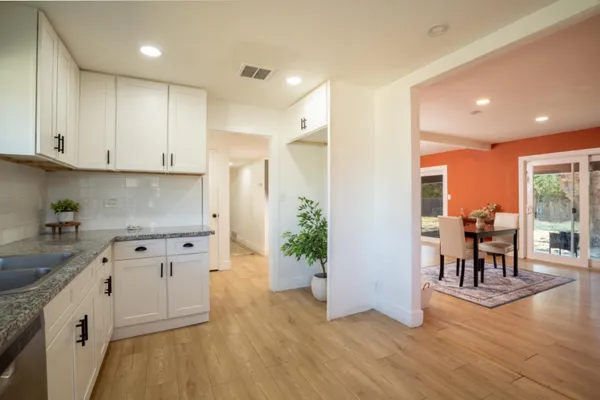 a kitchen with granite countertop a refrigerator a stove a dining table and chairs with wooden floor