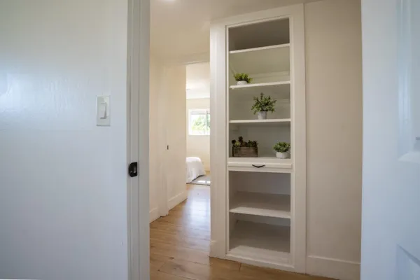 a view of a hallway with wooden floor and a cabinet
