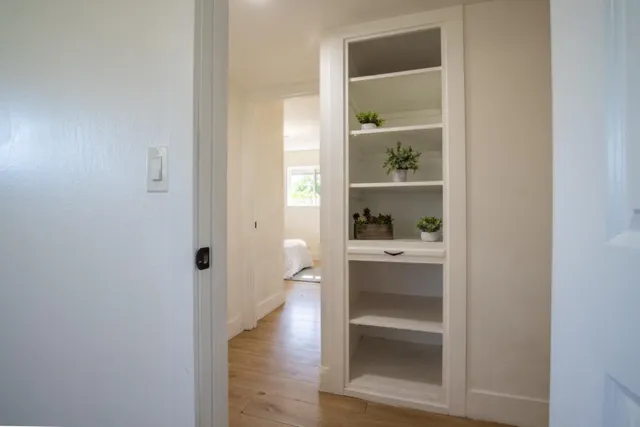 a view of a hallway with wooden floor and a cabinet