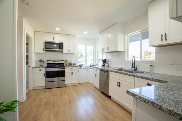 a kitchen with kitchen island granite countertop a sink cabinets and stainless steel appliances