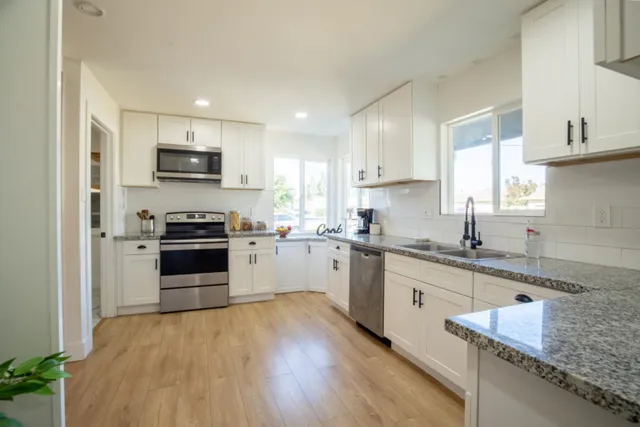 a kitchen with kitchen island granite countertop a sink cabinets and stainless steel appliances