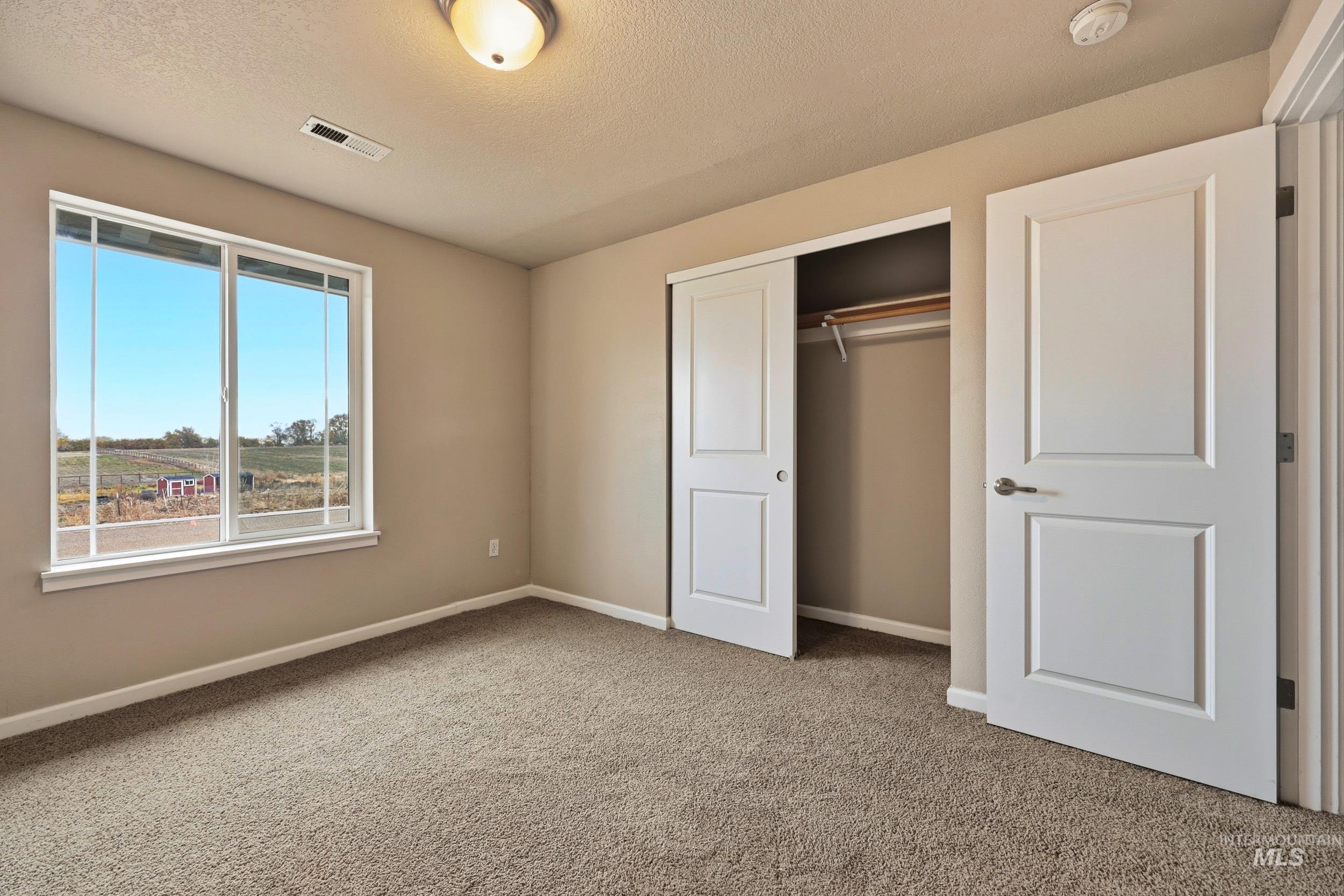 20203 Top Road Greenleaf, ID 83626 - Photo 15 of 16 Unfurnished bedroom featuring light colored carpet, a closet, and a textured ceiling