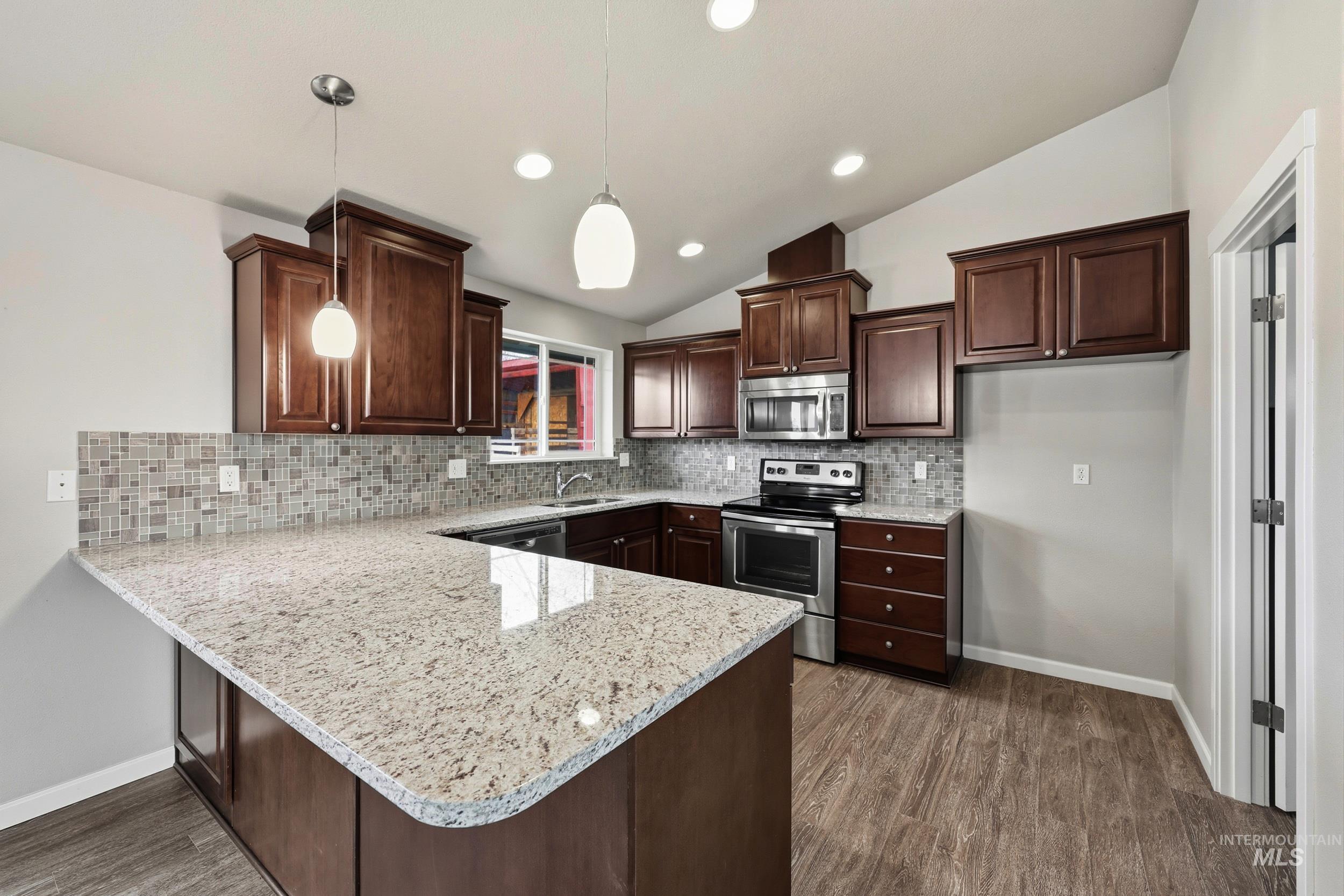 20203 Top Road Greenleaf, ID 83626 - Photo 4 of 16 Kitchen featuring lofted ceiling, dark brown cabinets, appliances with stainless steel finishes, hanging light fixtures, and a peninsula