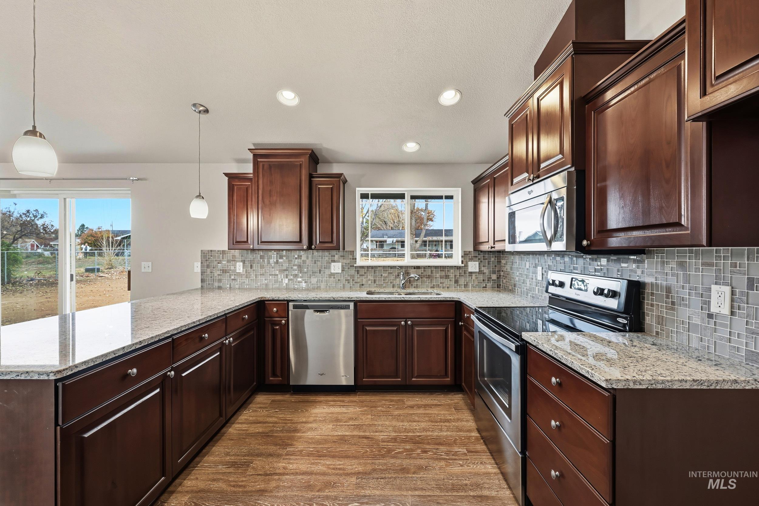 20203 Top Road Greenleaf, ID 83626 - Photo 5 of 16 Kitchen with stainless steel appliances, light stone countertops, recessed lighting, dark wood-type flooring, and pendant lighting
