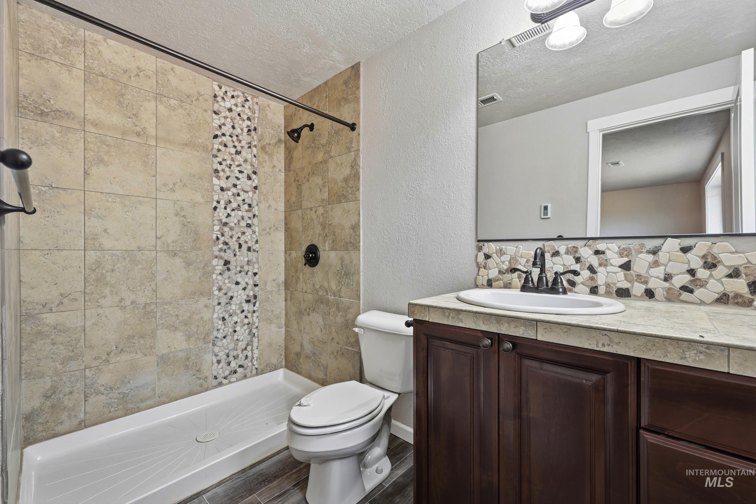 20203 Top Road Greenleaf, ID 83626 - Photo 7 of 16 Full bath with a textured wall, a textured ceiling, vanity, a shower stall, and decorative backsplash