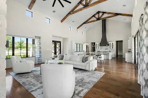 a living room with couches and kitchen view with wooden floor