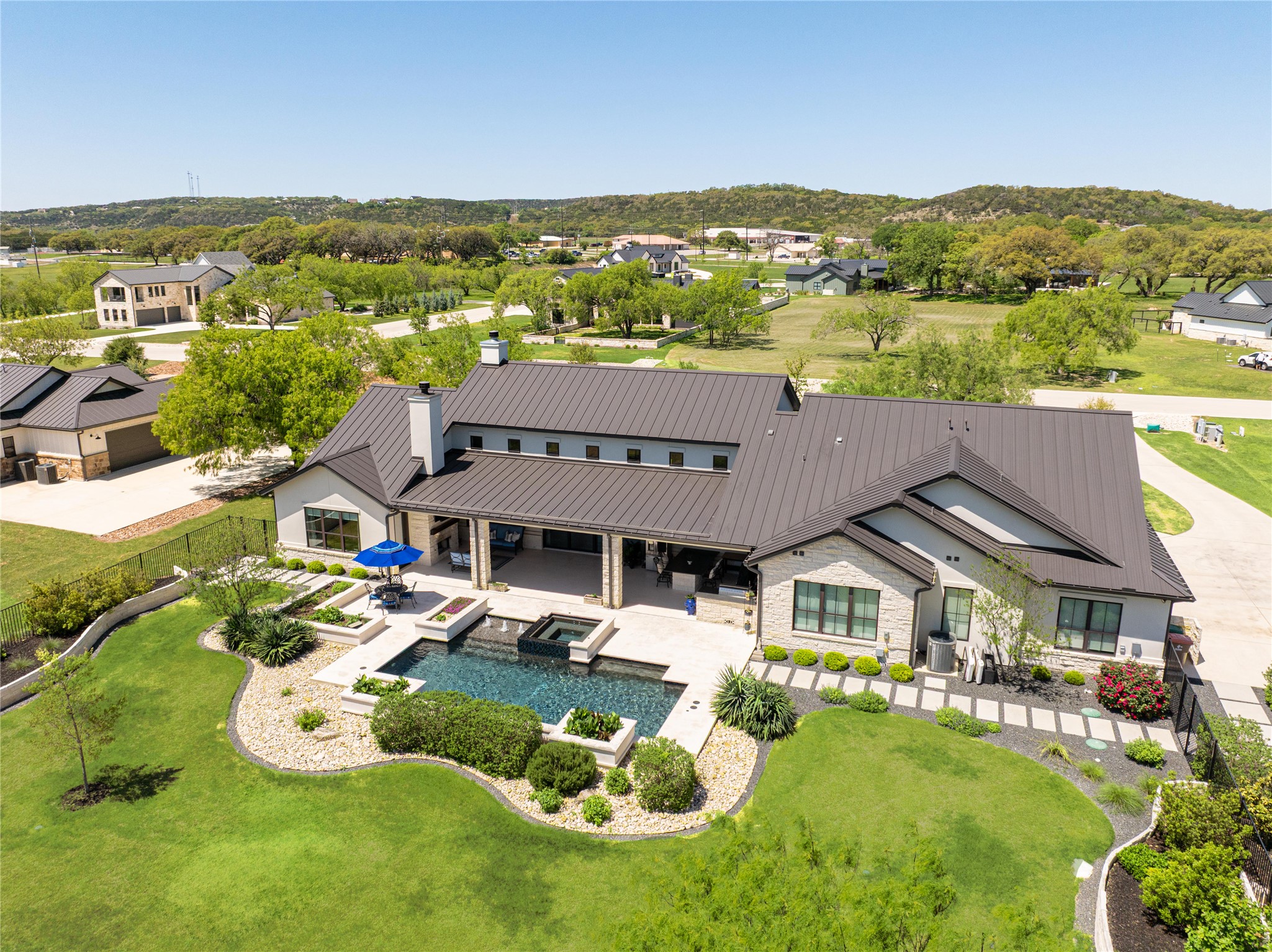 811 Wade Road Canyon Lake, TX 78132 - Photo 35 of 40 Rear view of property with a chimney, a standing seam roof, a patio, a residential view, and a pool with connected hot tub