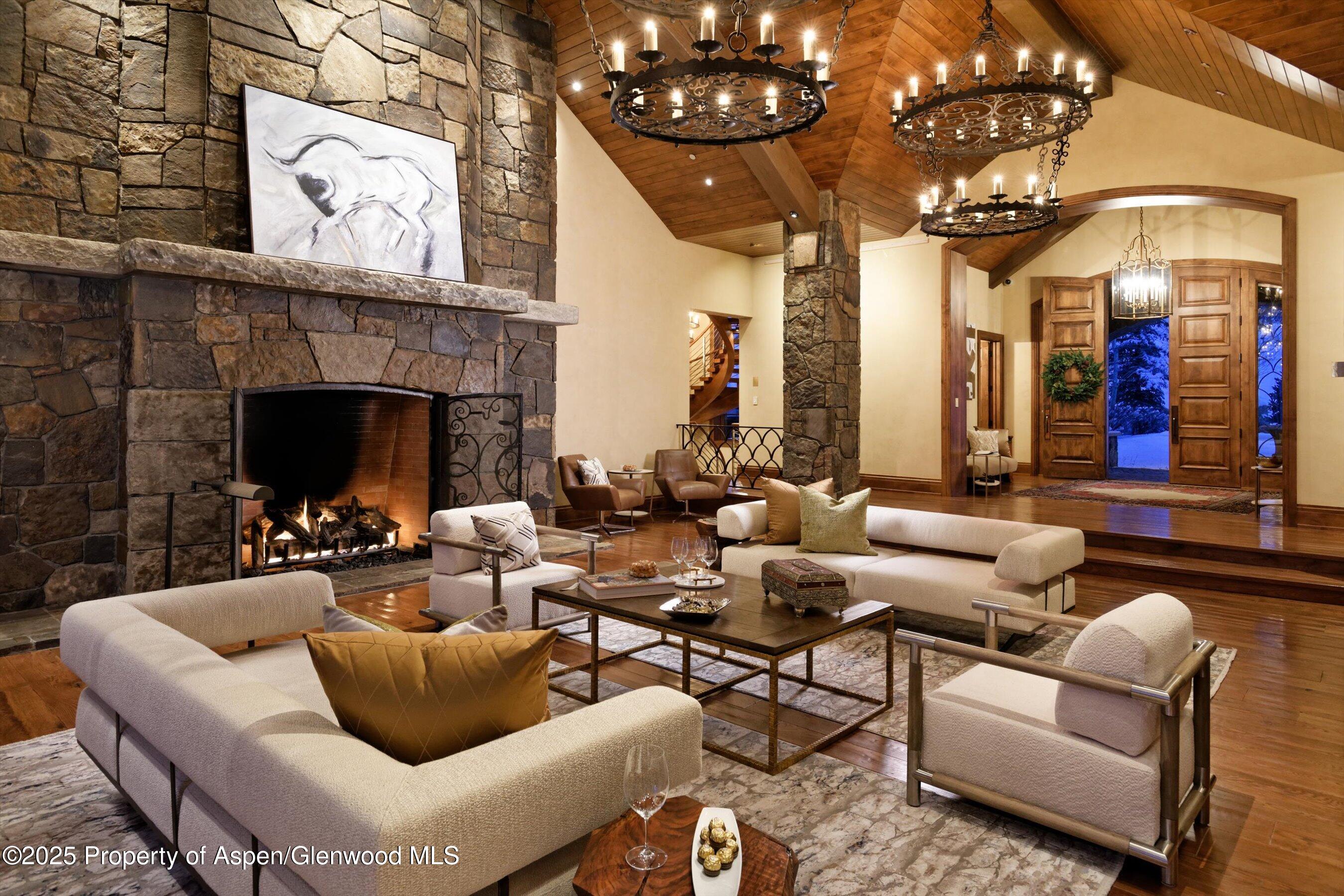 220 Buttermilk Lane Aspen, CO 81611 - Photo 27 of 60 a living room with furniture a chandelier and a fireplace