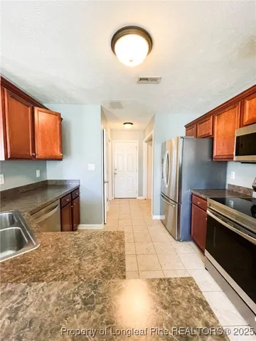 a kitchen with stainless steel appliances kitchen island granite countertop a refrigerator and a stove top oven