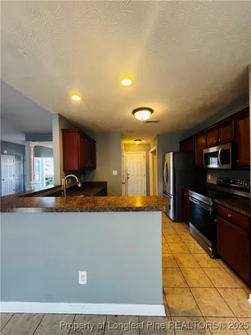 a view of a kitchen with kitchen island a sink a counter top space and stainless steel appliances