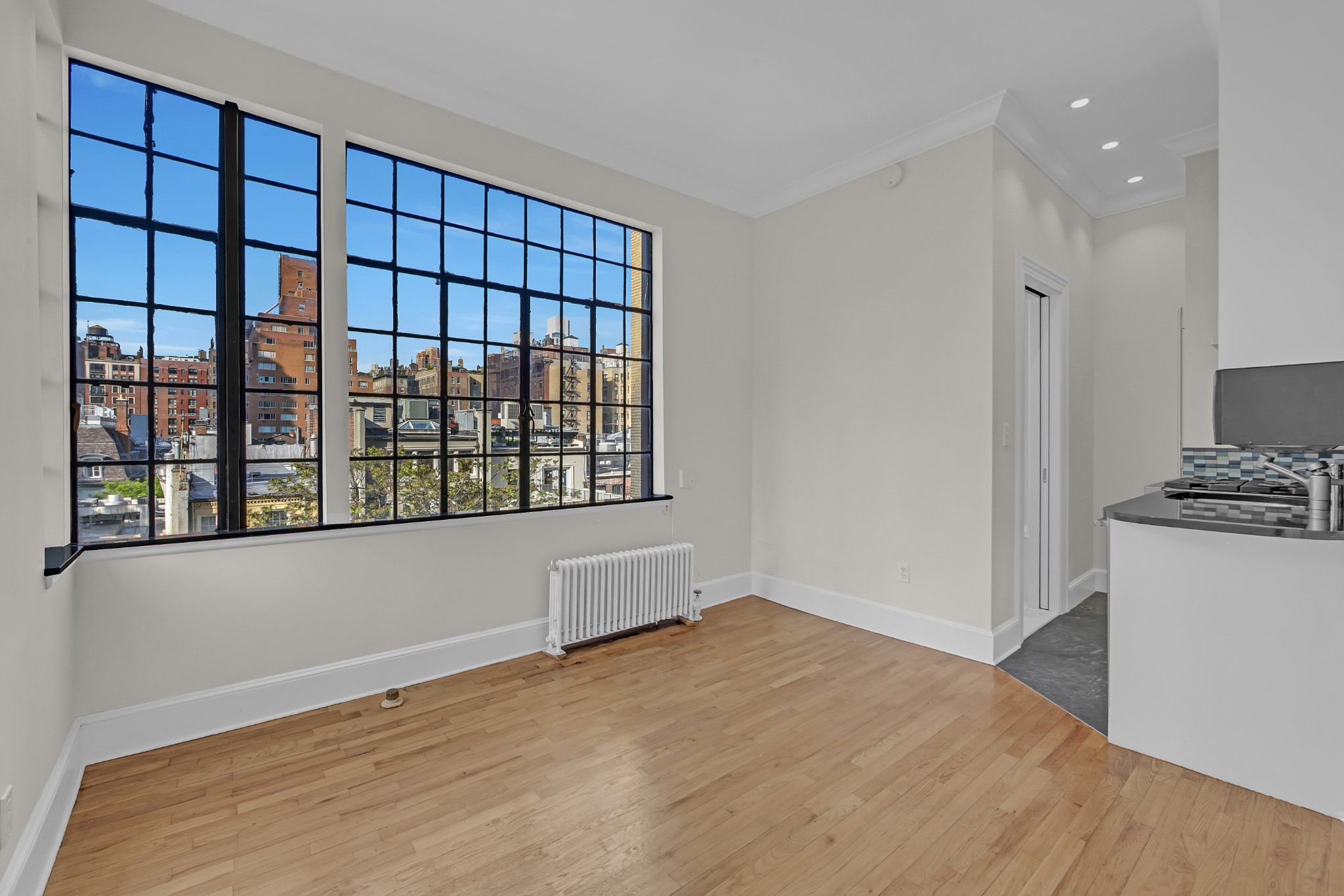 a view of an empty room with a window and wooden floor