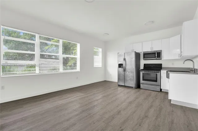 a view of kitchen with wooden floor electronic appliances and windows