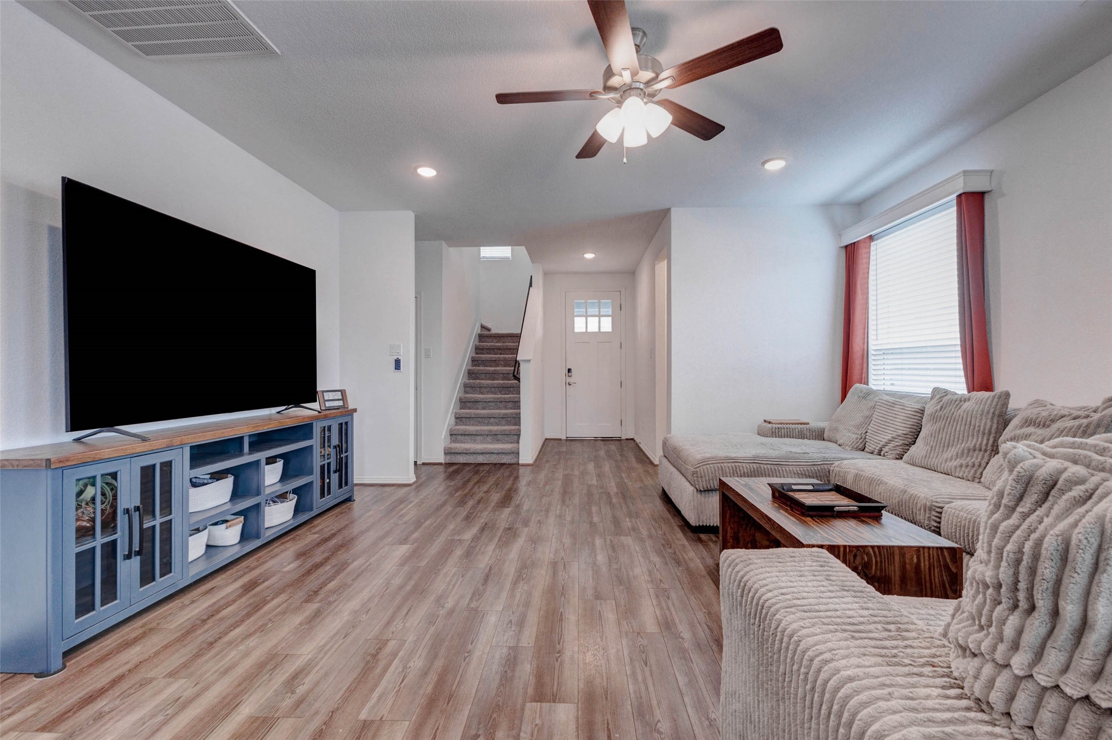 32418 Fly Fish Way Fulshear, TX 77441 - Photo 7 of 40 This angle of the living room showcases the ceiling fan, oversized windows that fill the space with natural light, and a generous wall that provides the perfect backdrop for a large entertainment center or media setup.